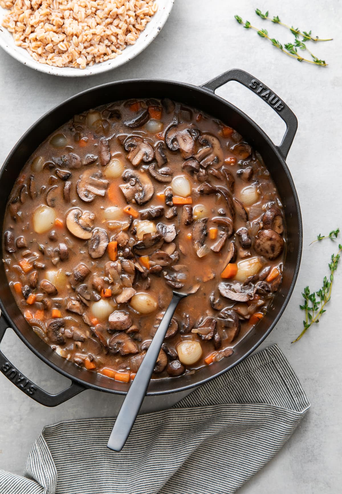 top down view of freshly made pot of vegan mushroom bourguignon with items surrounding.