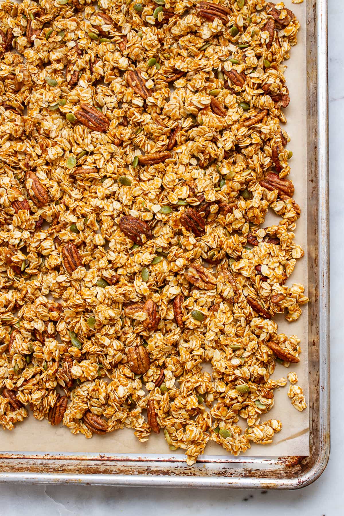 top down view of oil free pumpkin granola spread on a baking sheet before going into the oven to bake.