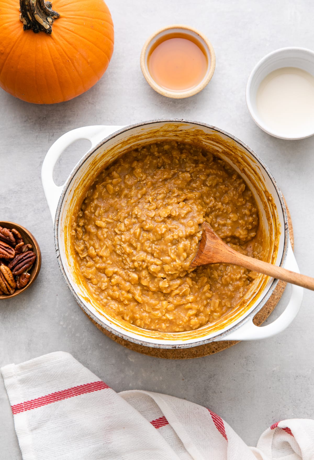 top down view of freshly made batch of the best pumpkin oatmeal in a pot with items surrounding.
