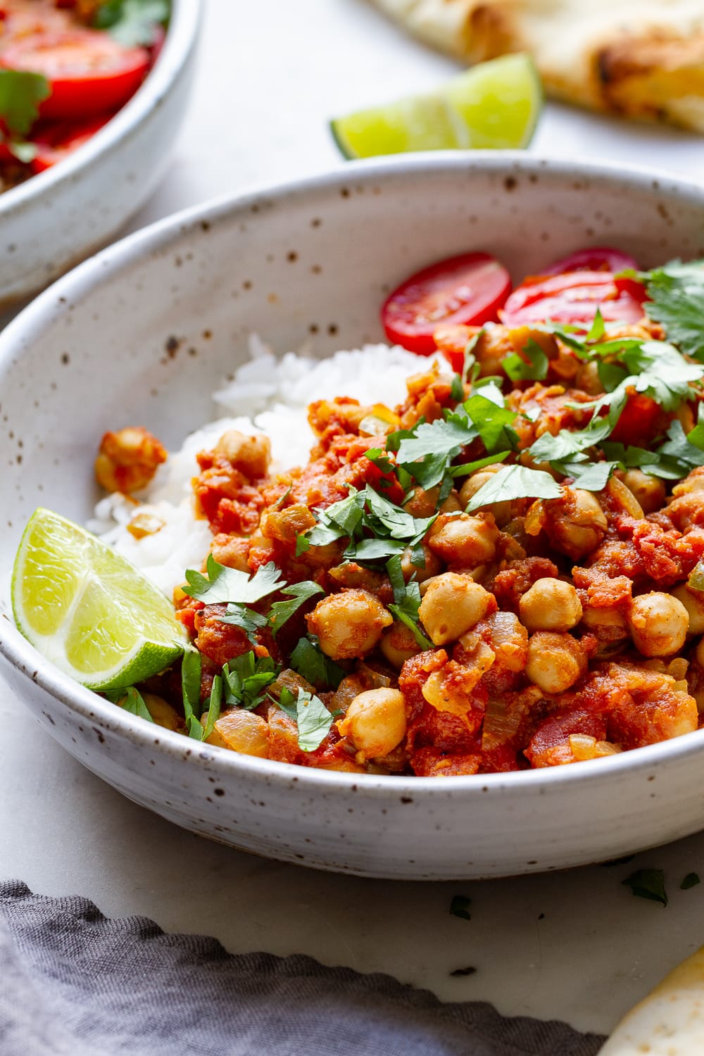 side angle view of easy chana masala in a bowl with rice, lime and cilantro.