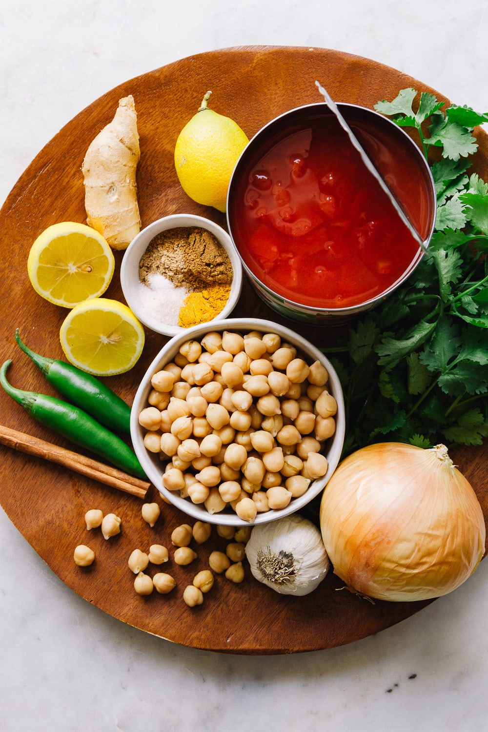 top down view of ingredients for easy chana masala recipe on a wooden charger.
