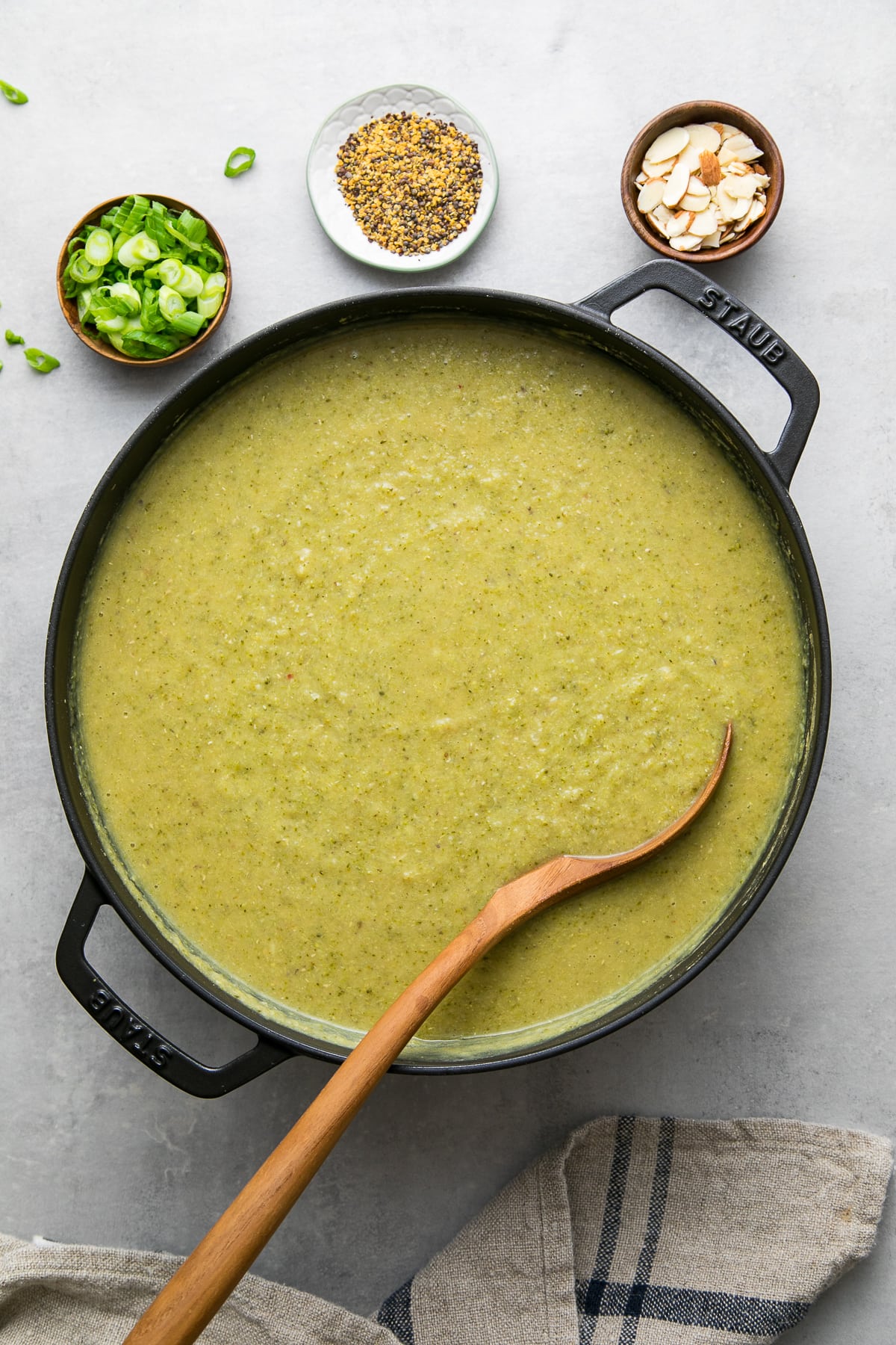 top down view of freshly made pot of vegan broccoli red lentil soup with items surrounding.