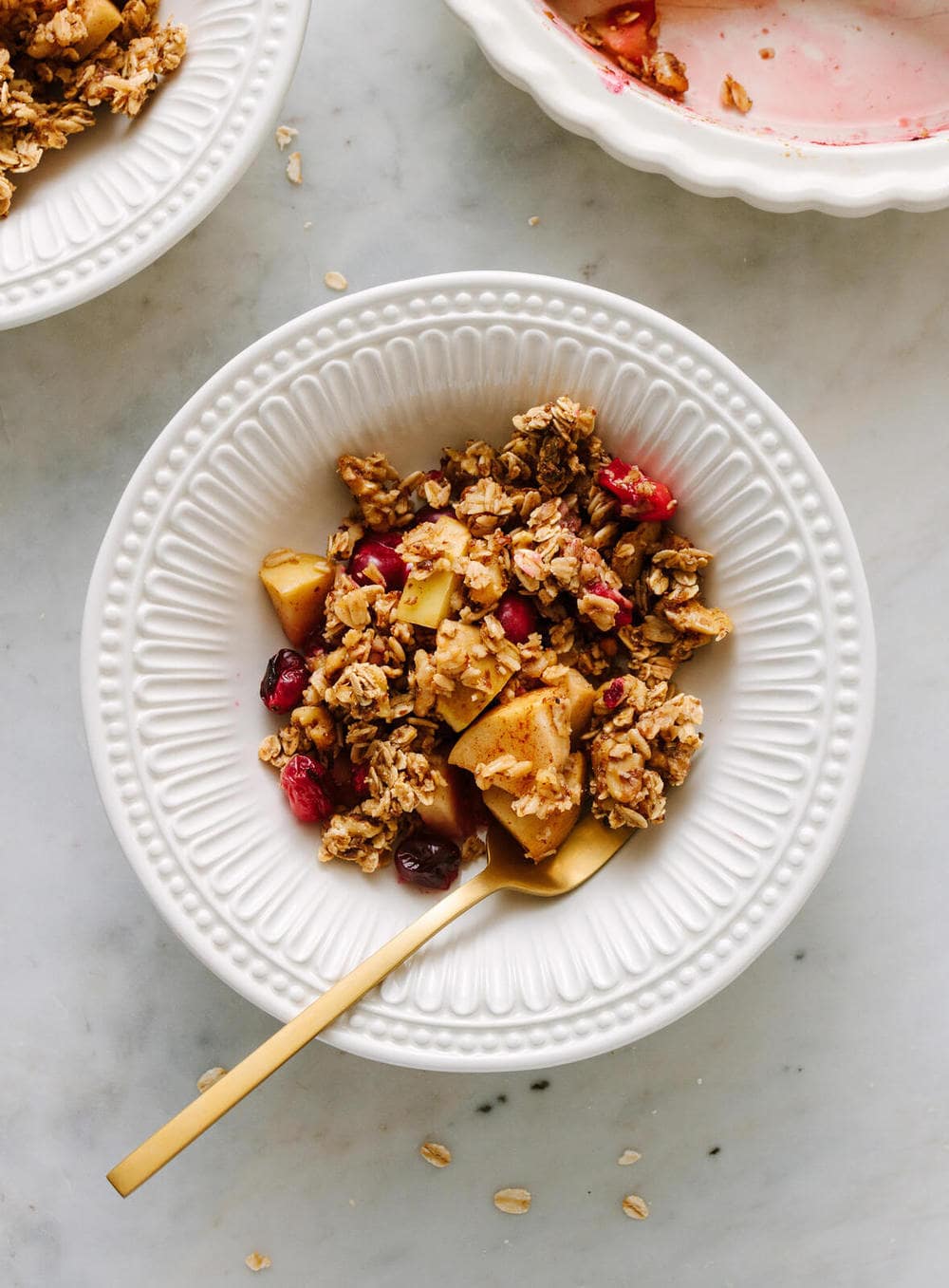 healthy apple cranberry crisp in a white bowl with fork